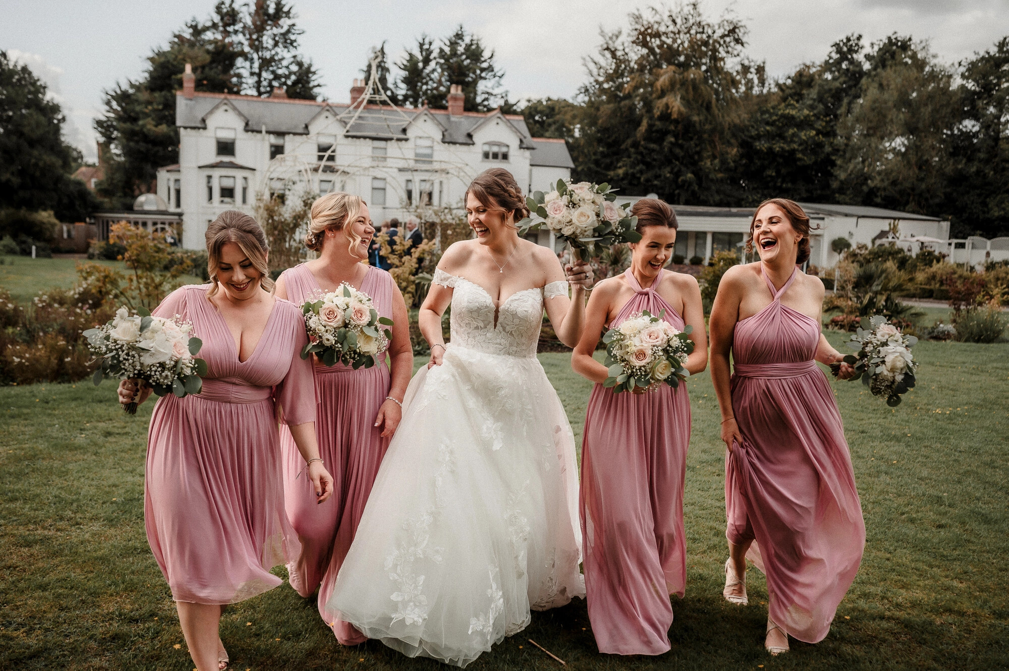 Bride and bridesmaids walking with pastel pink wedding flower bouquets