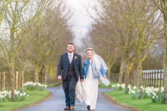 Bride and groom walking down treelined driveway