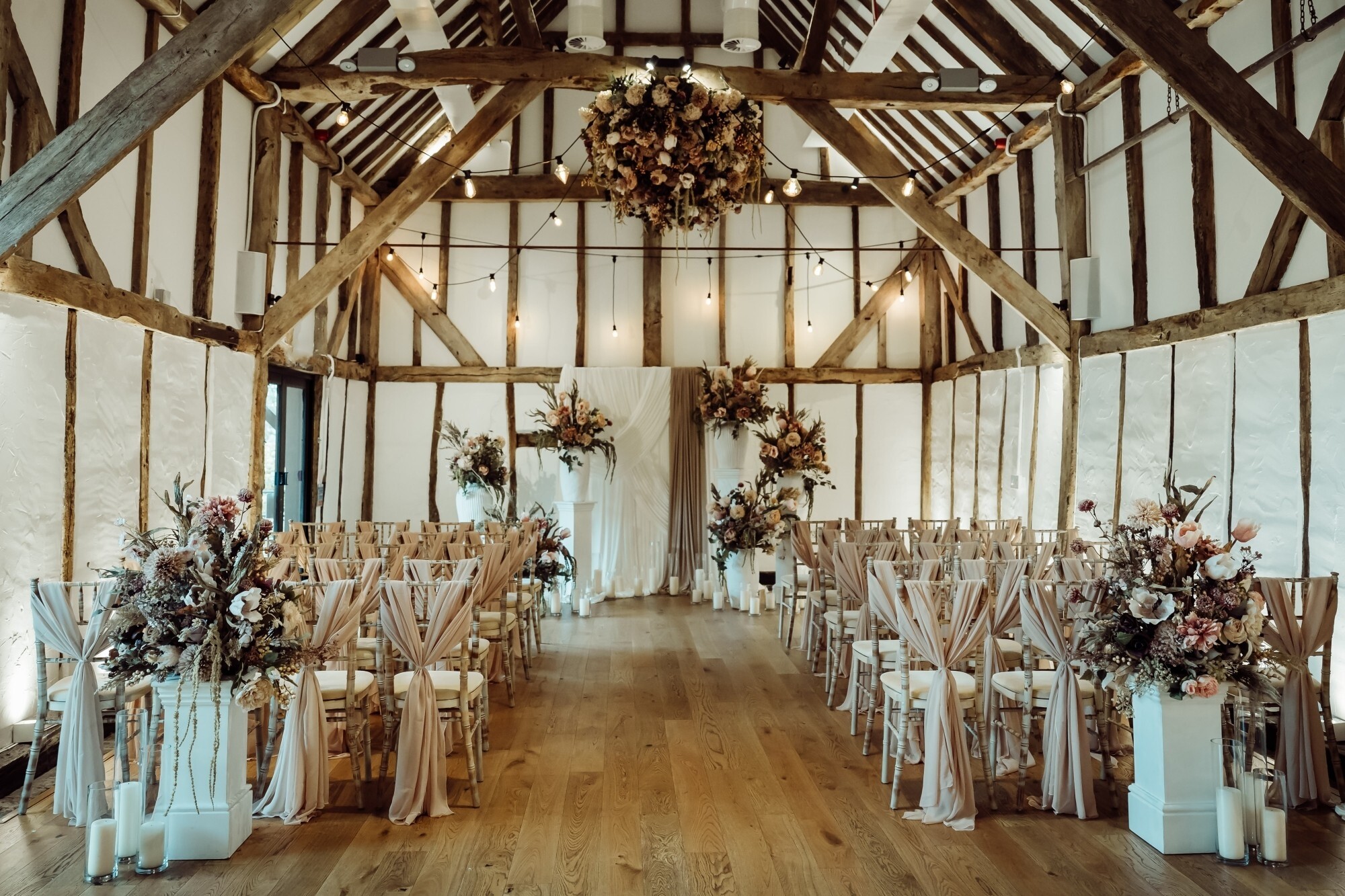 A twilight wedding ceremony set up in The Century Barn at Alfriston Gardens, wedding venue in East Sussex