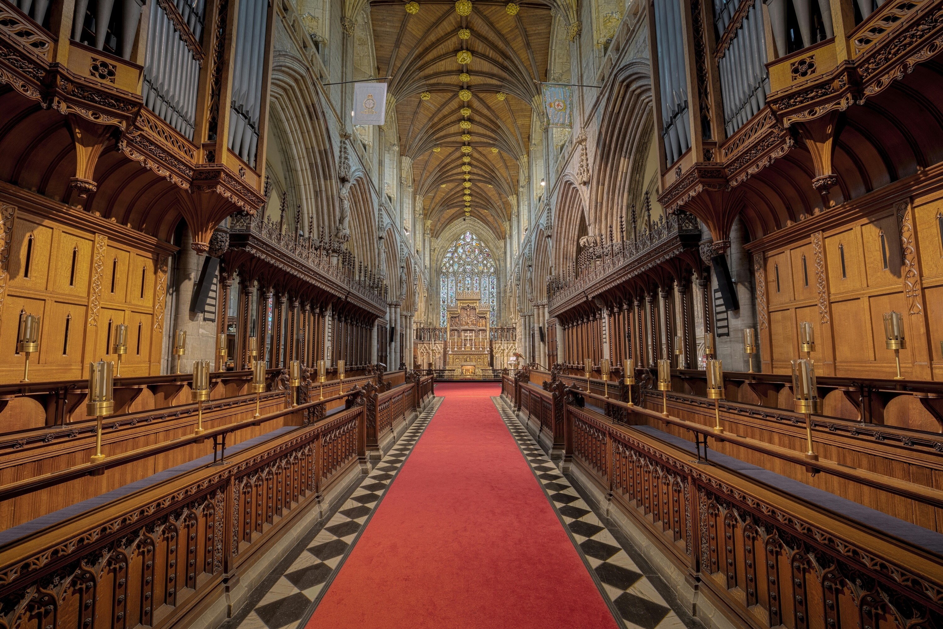 Interior of Westminster Abbey, London, with Gothic architecture, carved wooden choir stalls and red aisle