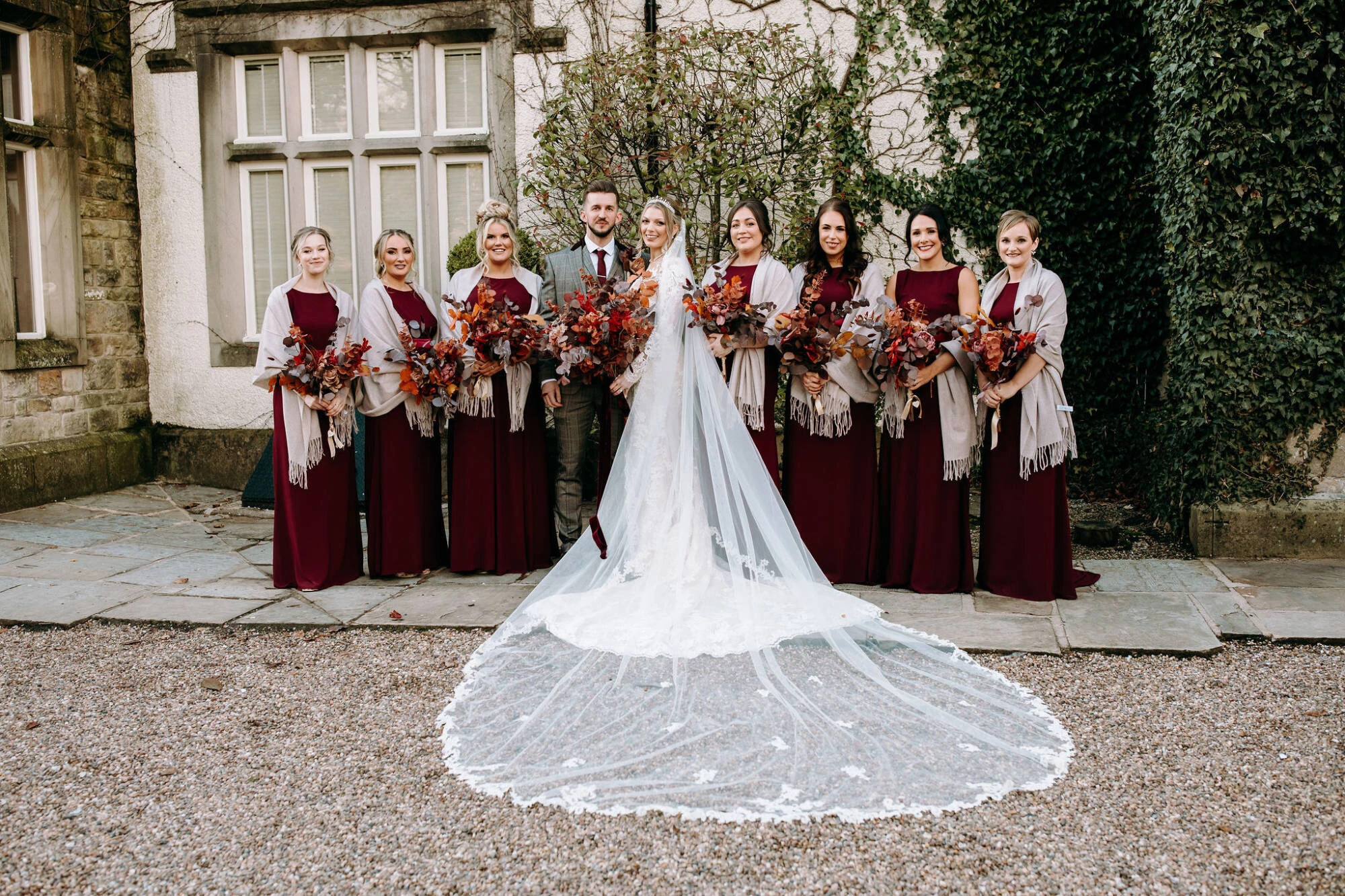 Bride and bridesmaids holding jewel tone wedding bouquets with amber and red flowers for formal photographs