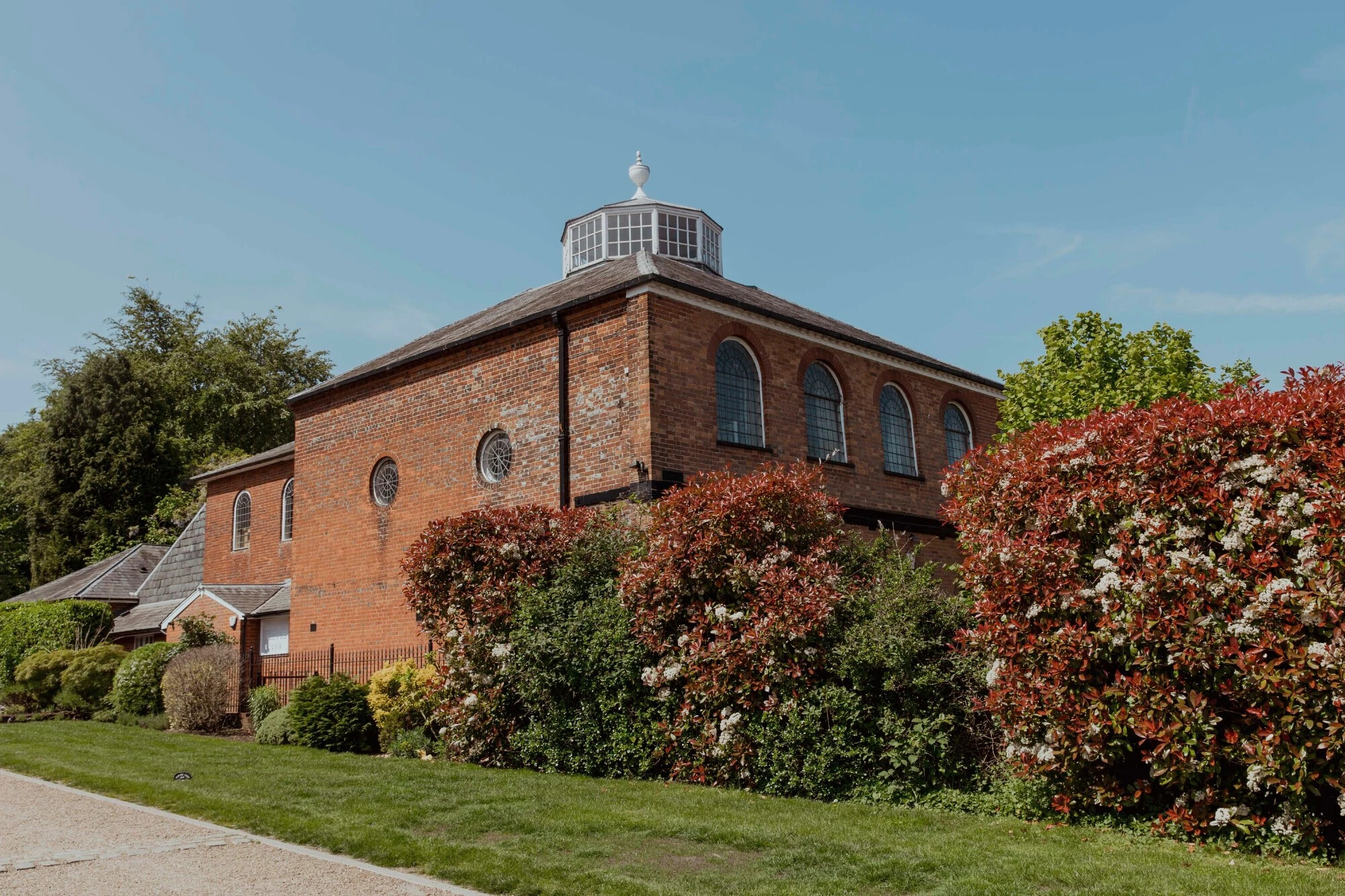 Exterior view of Kings Chapel Old Amersham, a red brick wedding venue with arched windows and landscaped gardens.