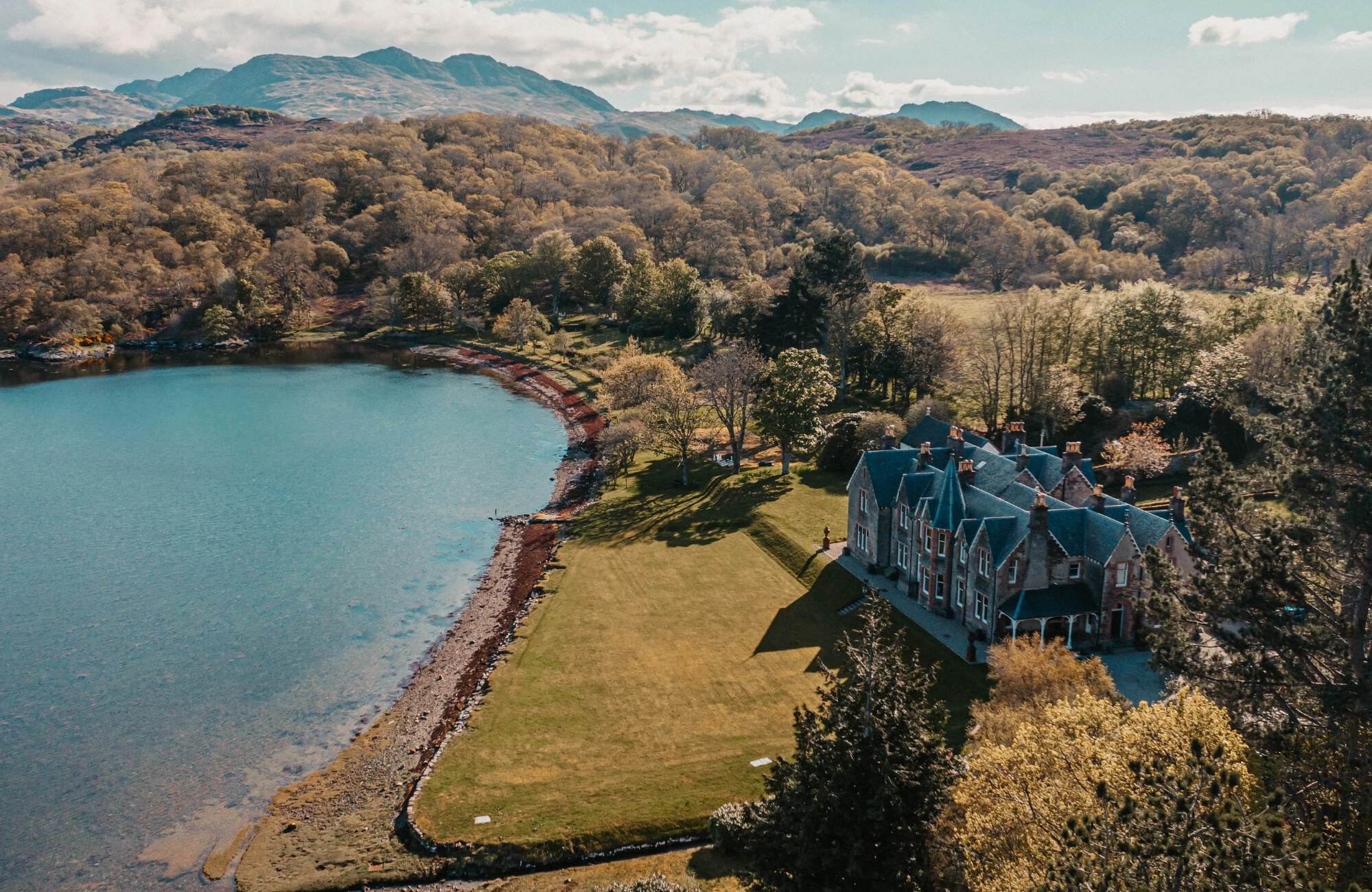 Drone image of a coastal hotel wedding venue with mountains behind the main building