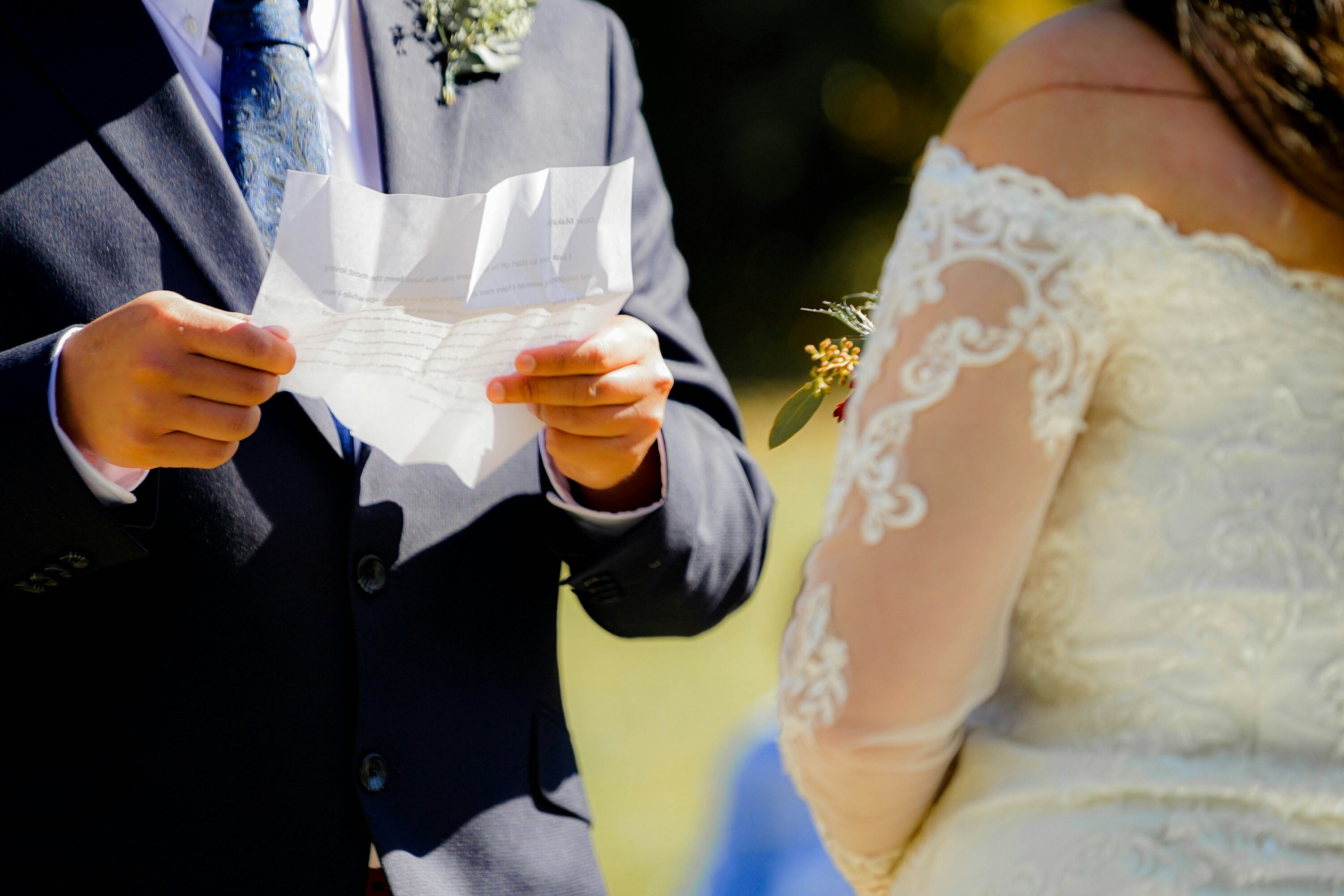 Groom holding paper with vows on, ready to read to bride