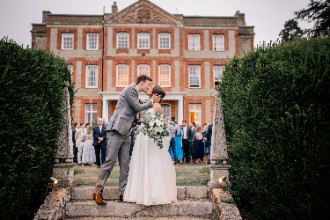 Bride and groom kissing in front of Ardington House