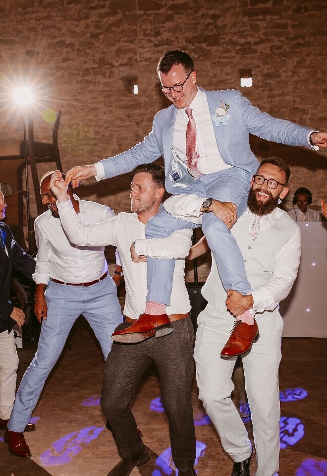 Groom being carried into wedding reception dance floor at Cogges Manor Farm wedding venue