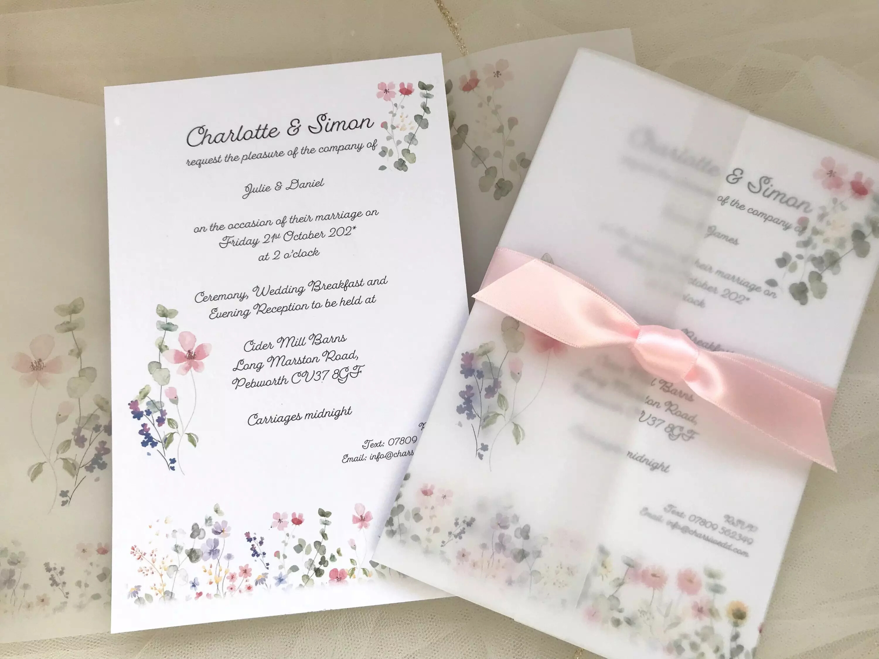 Daisy Chain Invites wedding invitation suite featuring soft floral illustrations, a printed invitation card and a vellum cover tied with a pale pink ribbon.