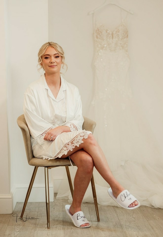 Chloe sitting on a chair with her wedding dress hanging beside her