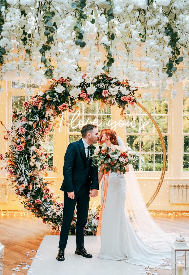 Bride and groom kissing at the top of the aisle 
