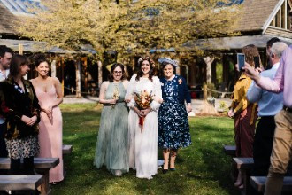 Bride, bridesmaid and mother walking down aisle at outdoor wedding ceremony