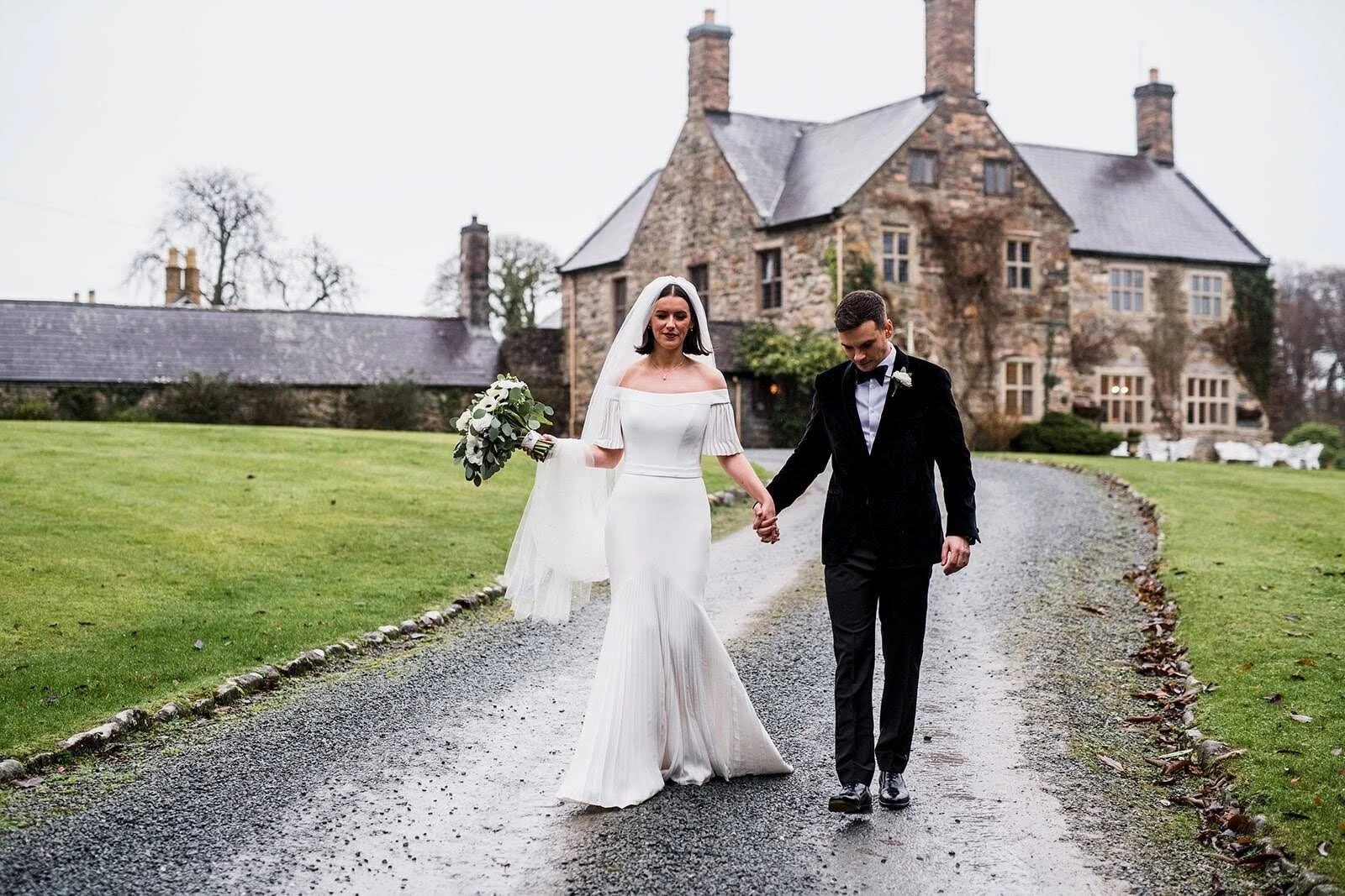 Bride and groom walking from their wedding venue, Talhenbont Hall, in Wales