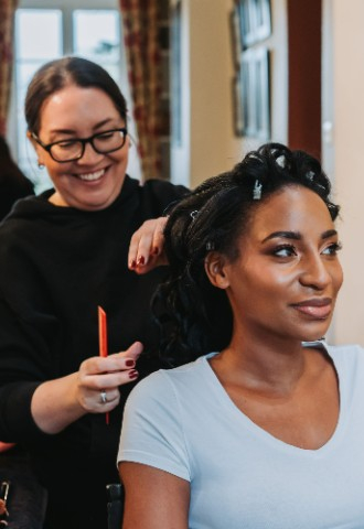 Lisa Murphy Make up and hair styling the brides hair, smiling.