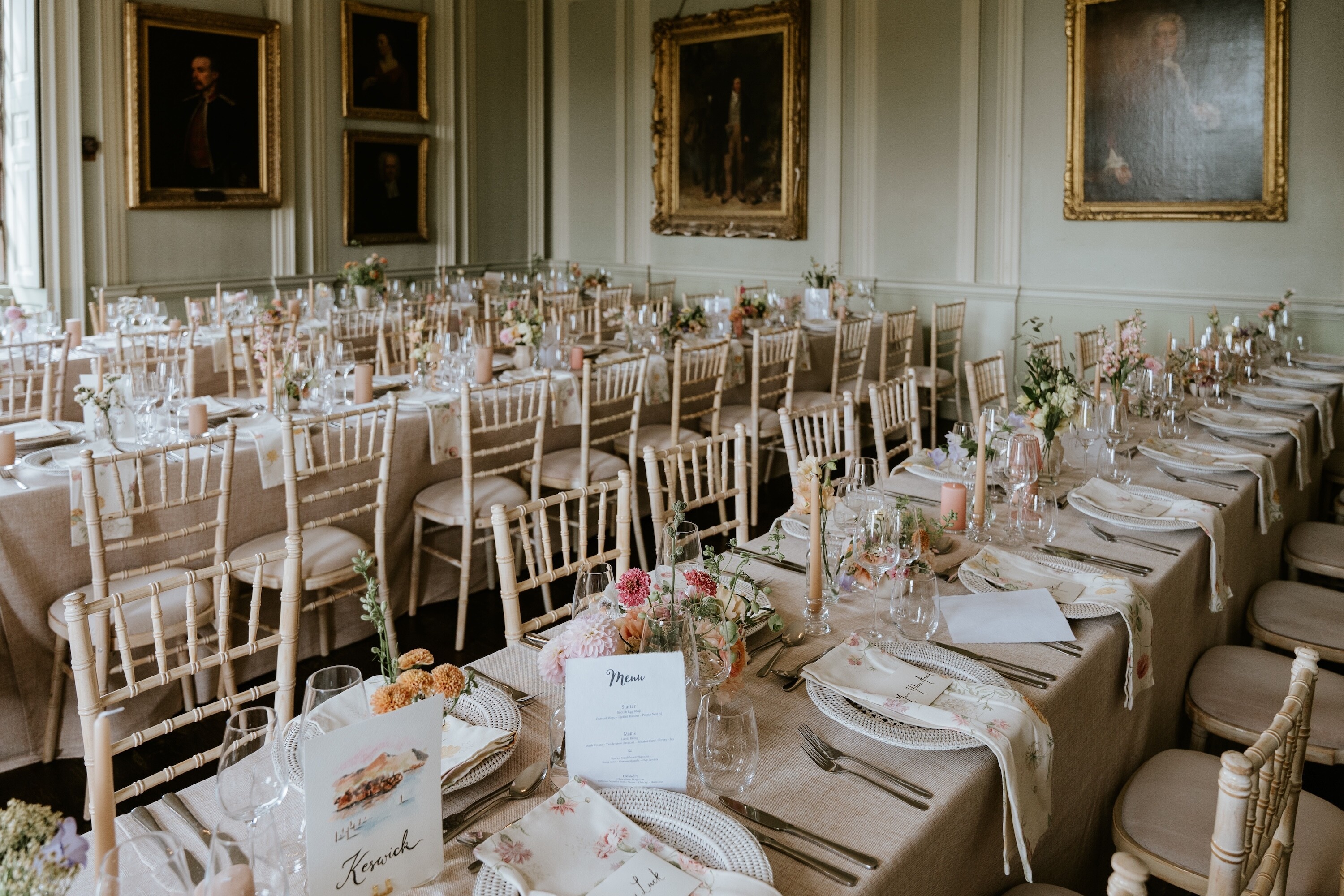 Romantic theme wedding reception setup in a historic dining room with long tables, floral linen, pastel flowers and candlelight styling.