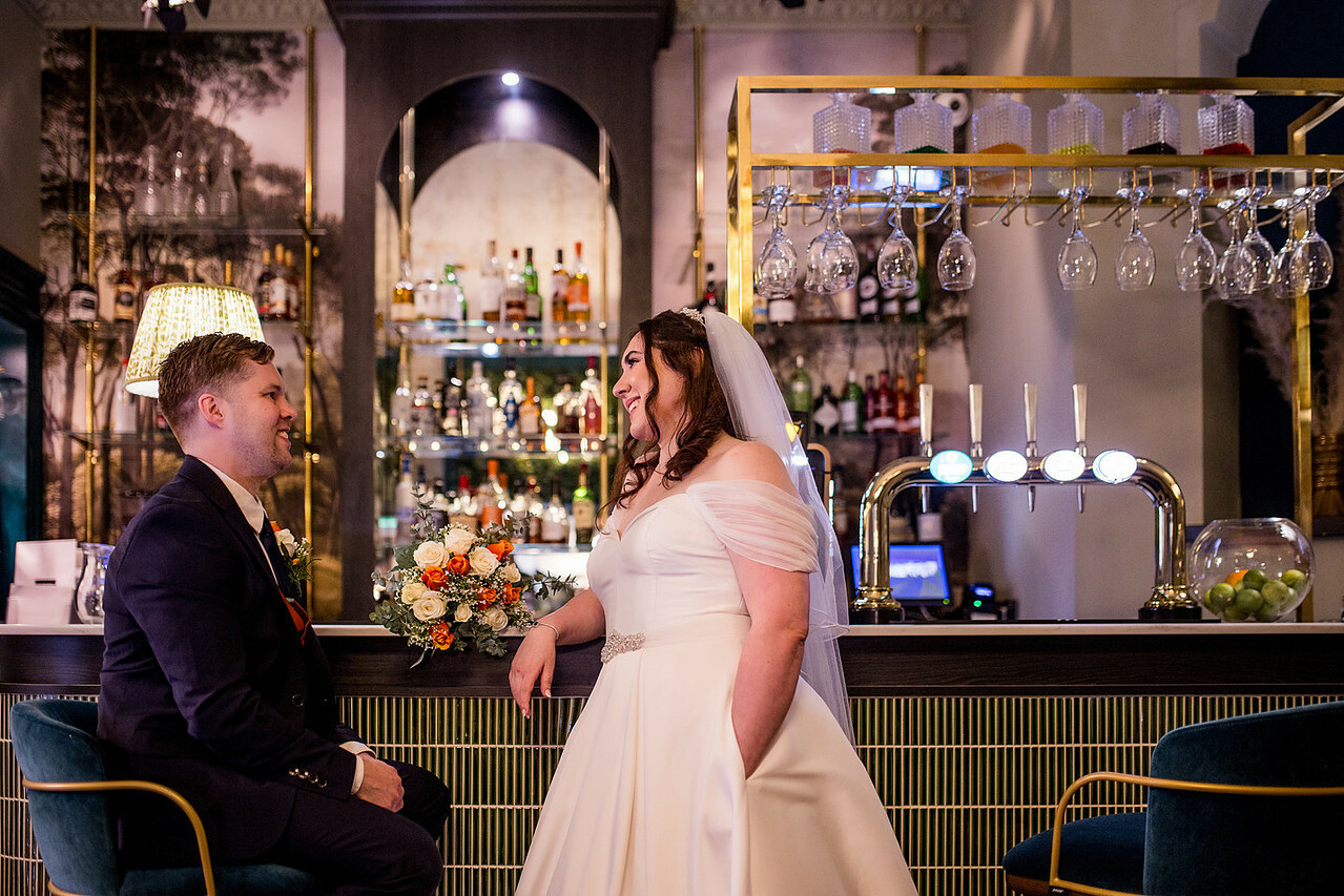 Bride and groom sat at the bar at Burnham Beeches Hotel