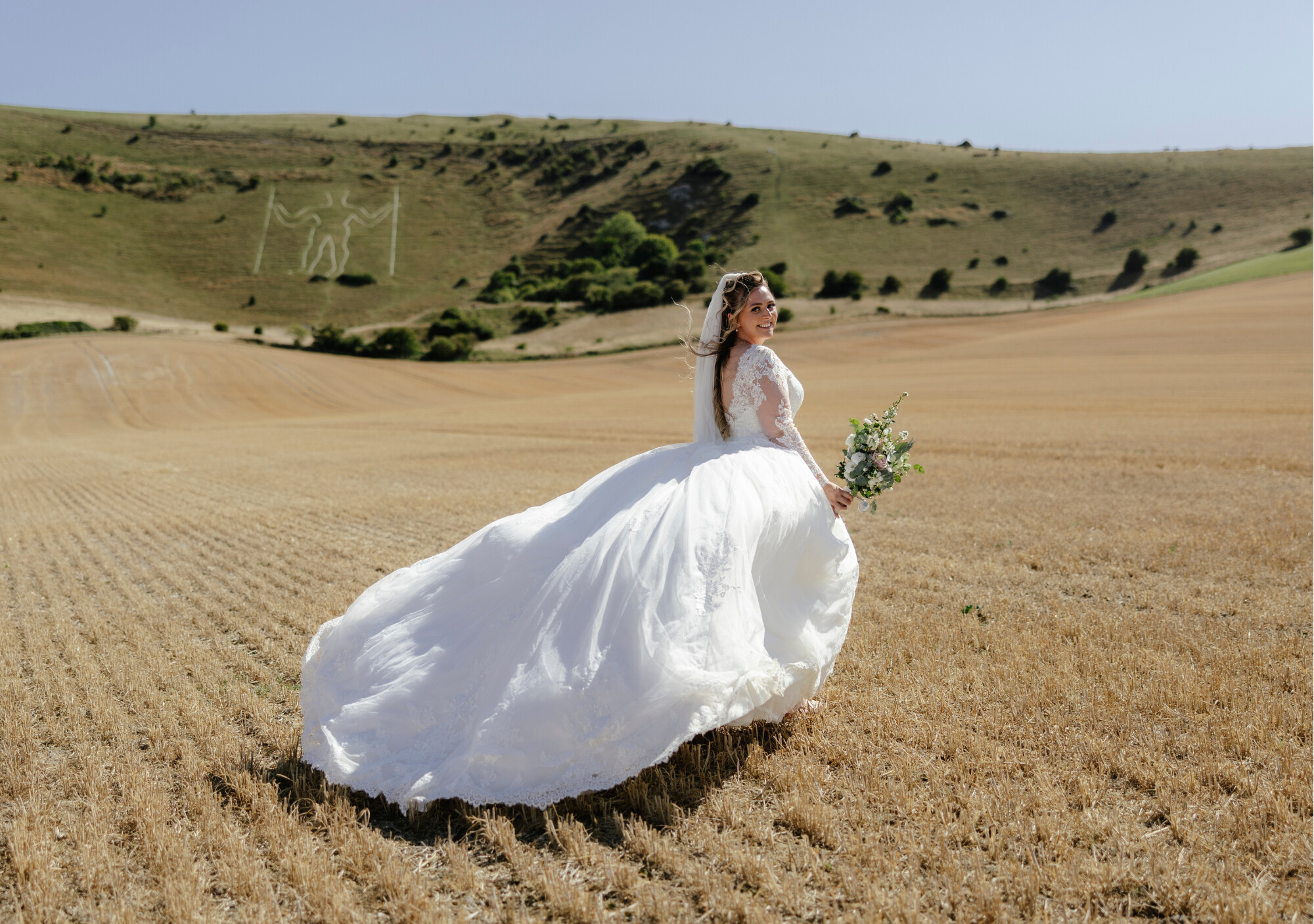 Bride taking wedding day portraits running through the cornfield at Alfriston Gardens