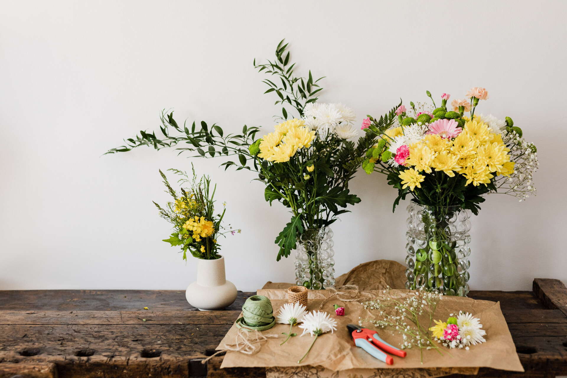 DIY wedding flower arrangements in glass vases with seasonal blooms and greenery