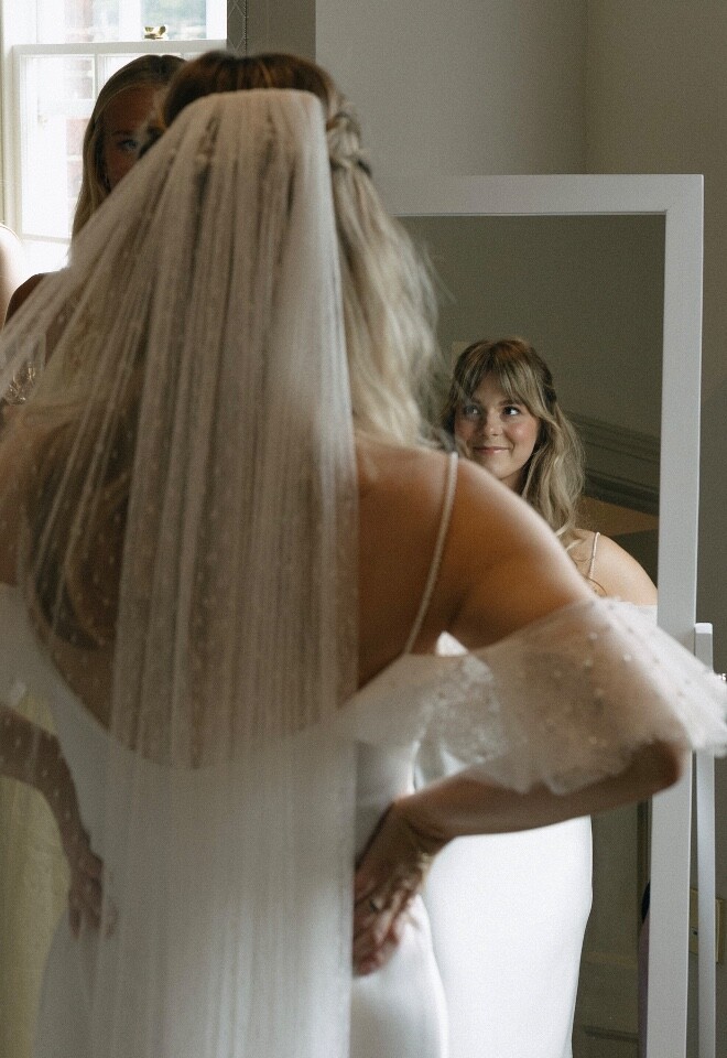 Bride in her wedding dress and veil getting ready.