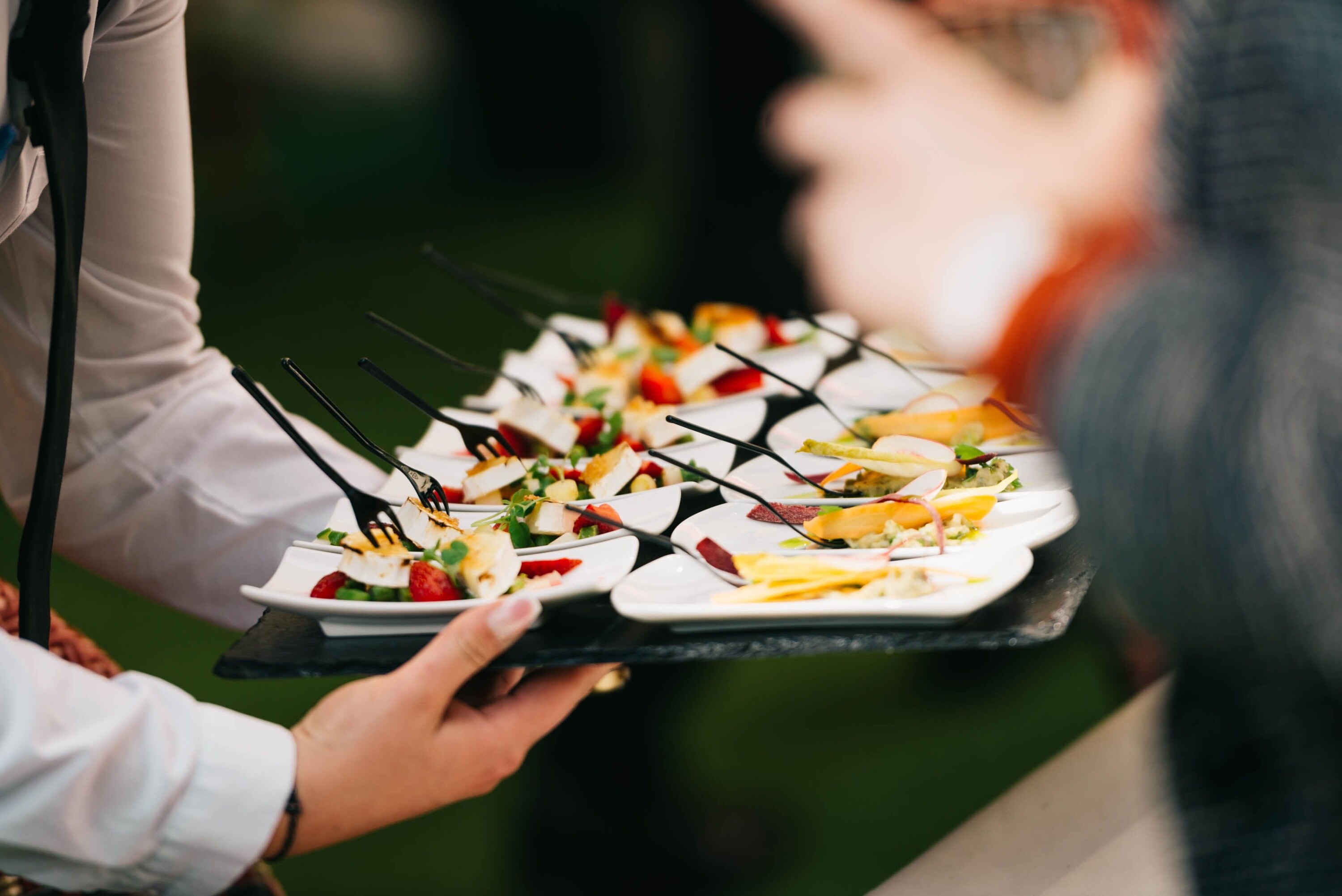 Waiter serving wedding canapés to guests during a drinks reception.