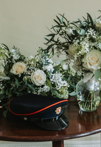 Detail photo of floral arrangements and military uniform hat on a table