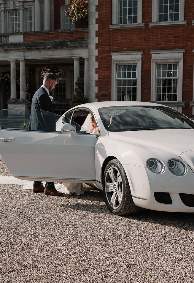 Bride and groom with the wedding car