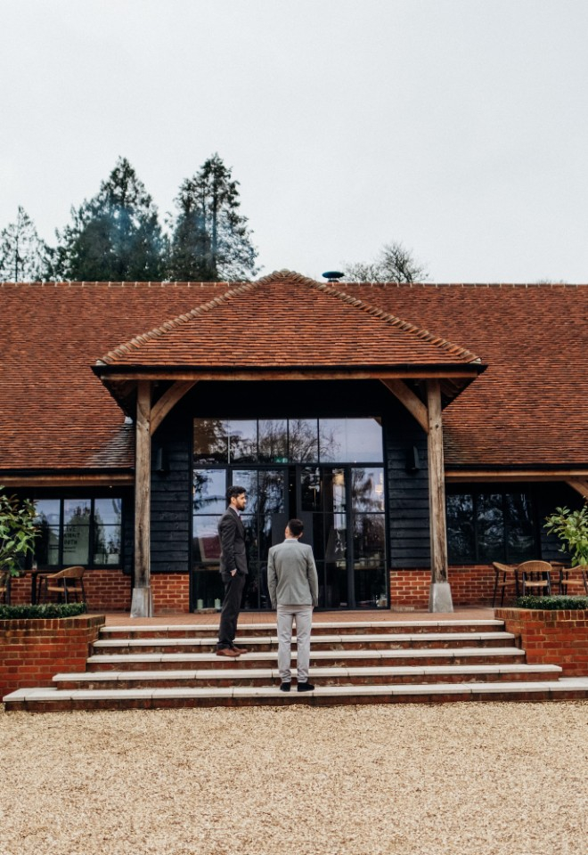 Exterior of post barn with wedding guests in front of the door