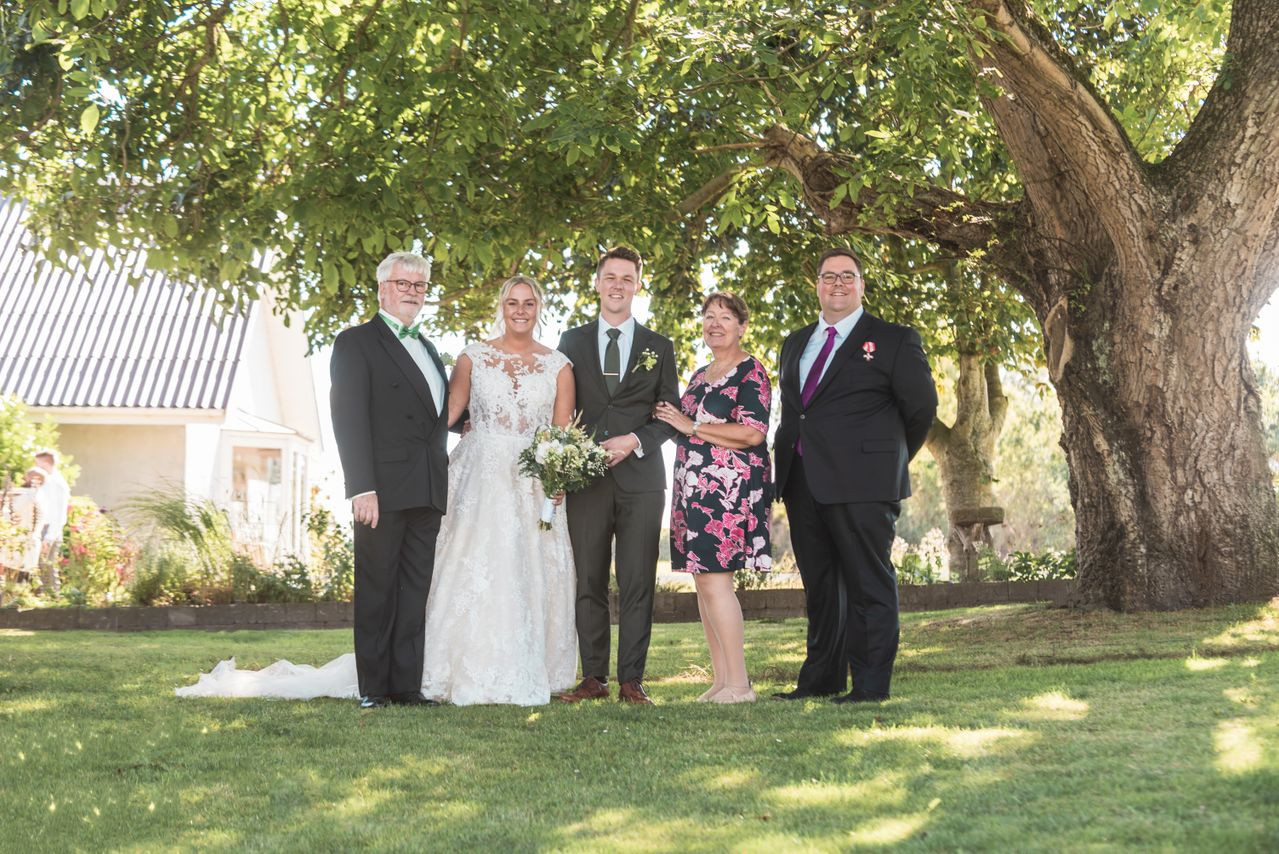Newlywed couple posing with family members for an outdoor wedding photograph