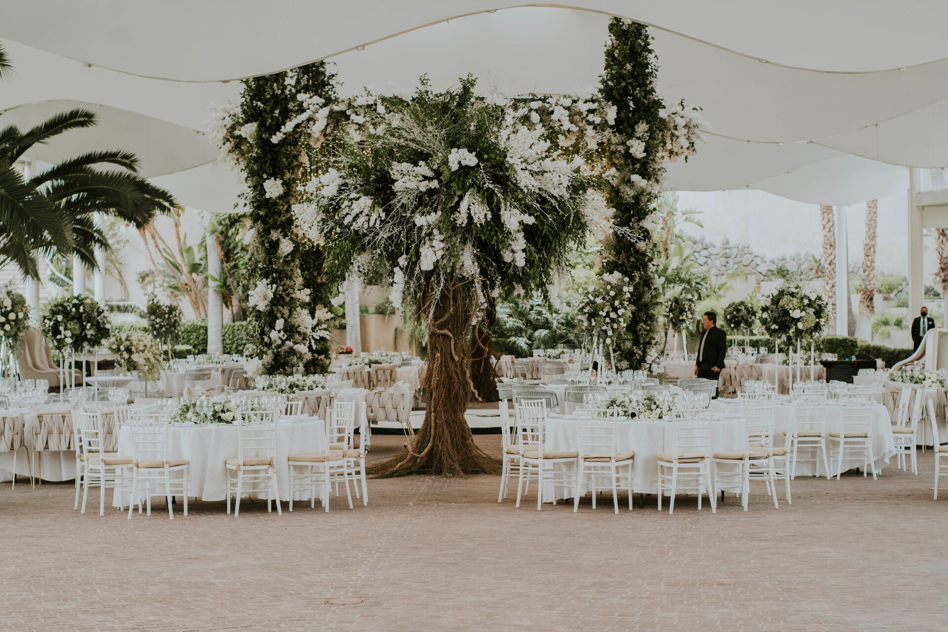 Luxury wedding reception featuring a dramatic floral installation and elegantly styled dining tables.