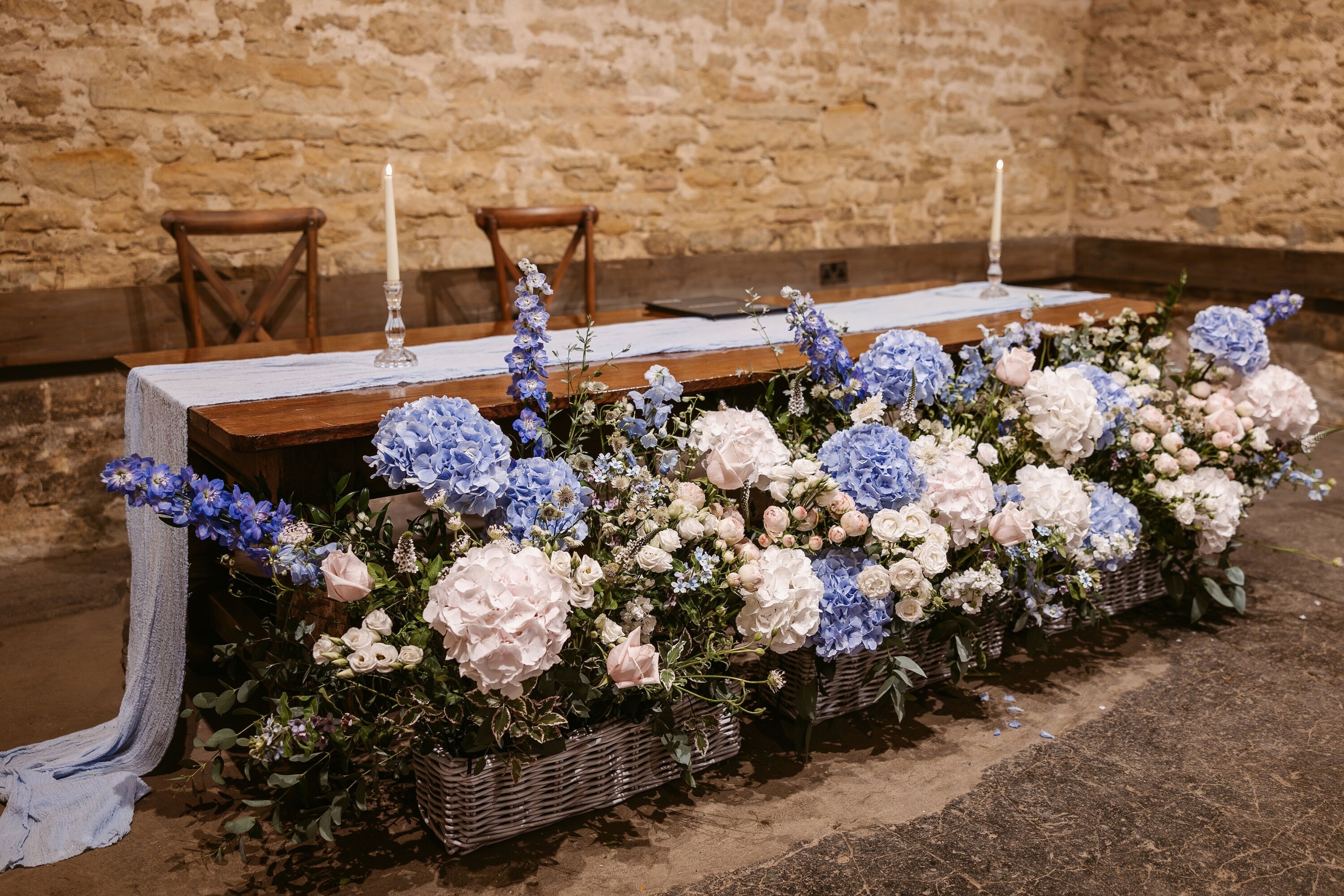 Cogges Barn wedding venue ceremony room showing blue, white and pink flowers for wedding decor
