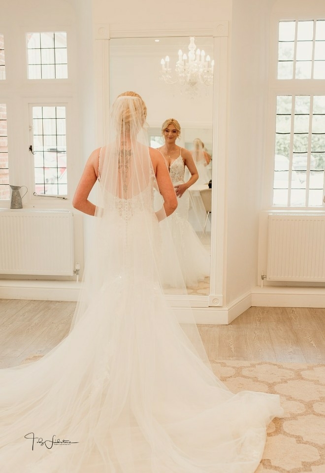 Chloe looking at herself in the mirror with her wedding dress on