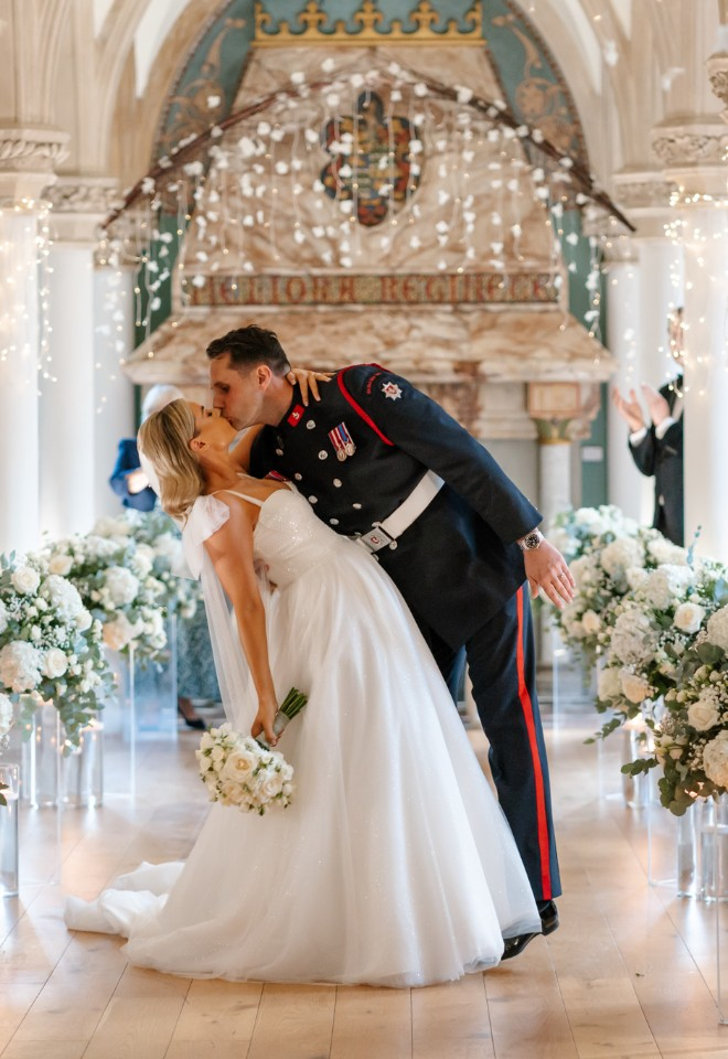 Dip kiss in the middle of the wedding aisle surrounded by flowers
