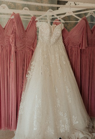 Bride and bridesmaid dresses hung up on bed frame at Southdowns Manor West Sussex