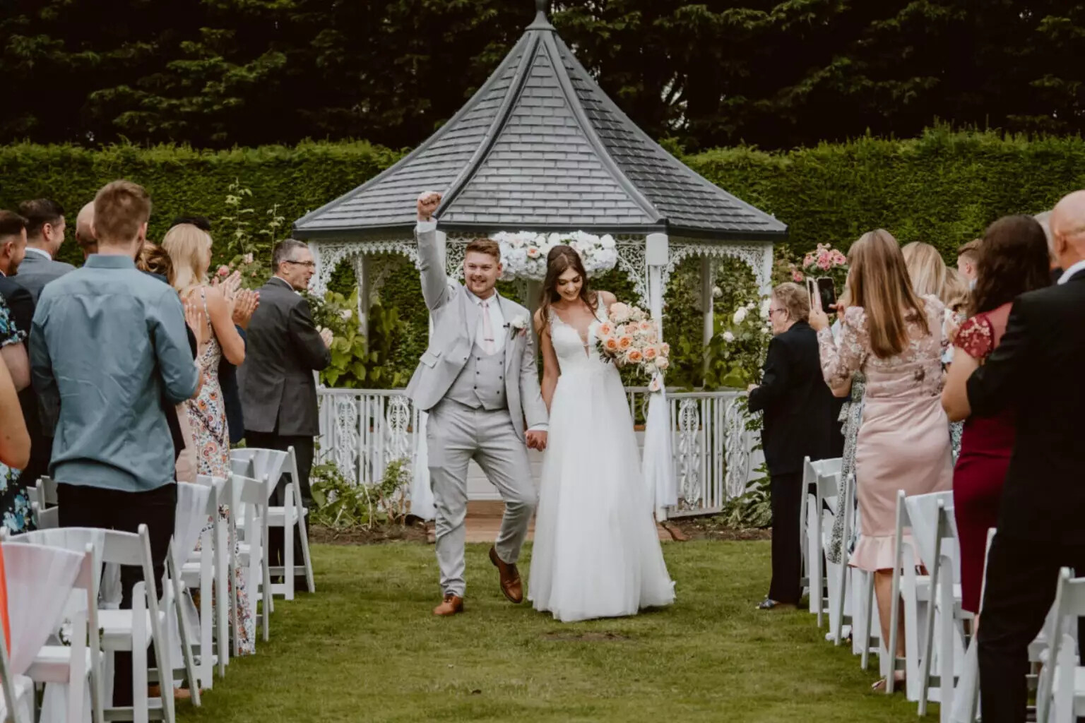 Couple celebrate walking down the aisle after outdoor wedding ceremony at Hockwold Hall