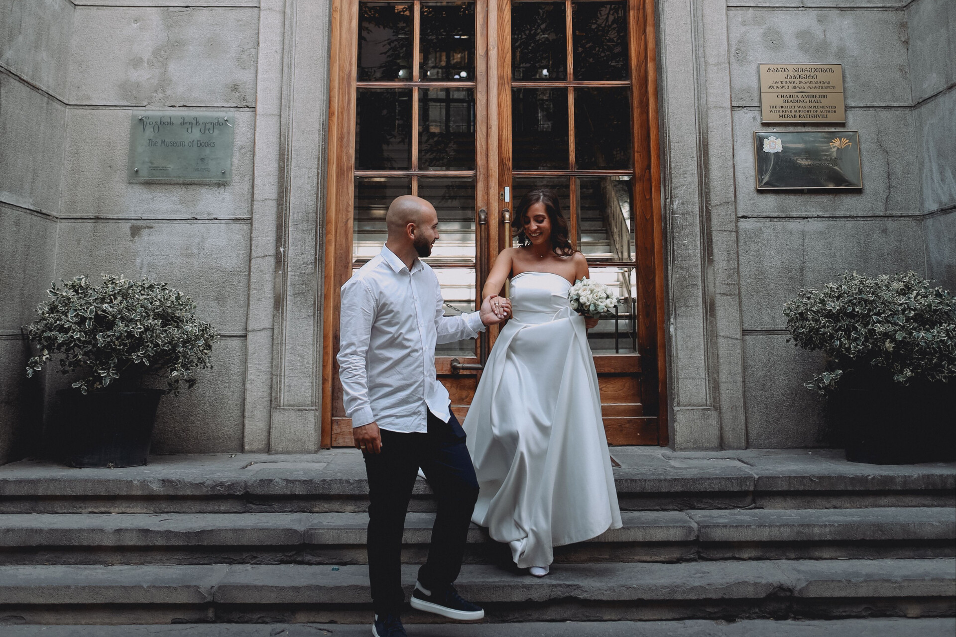 Newly married couple leaving a registry office and walking down stone steps together