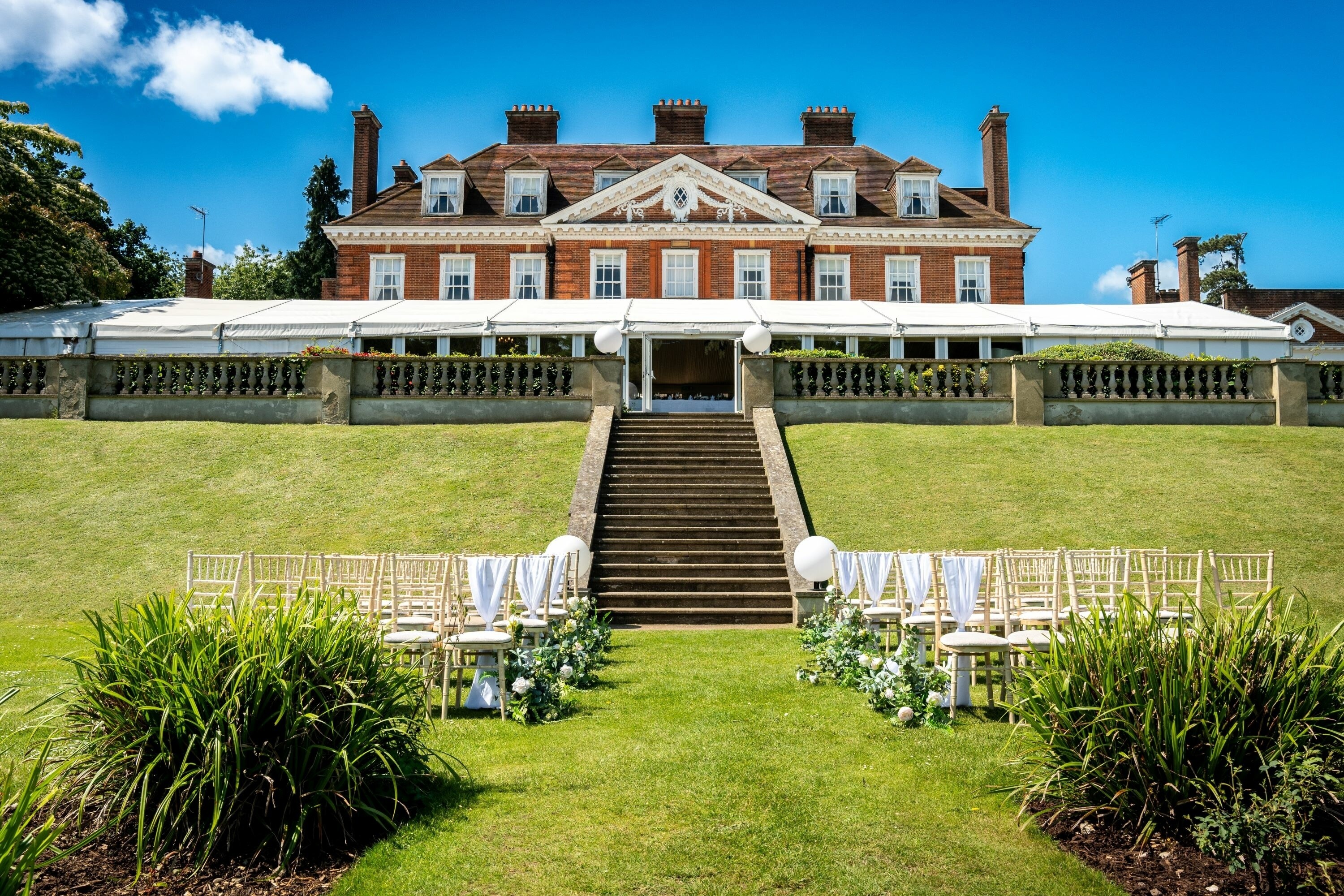 Outdoor wedding ceremony setup at Hunton Park Hotel with aisle seating leading up to the historic house and terrace
