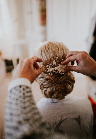 Floral hair pin being placed in brides hair at Hedsor House wedding venue Buckinghamshire