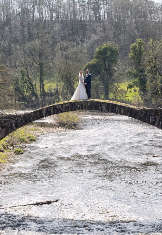 bride and groom zoomed out photo on a bridge over the river