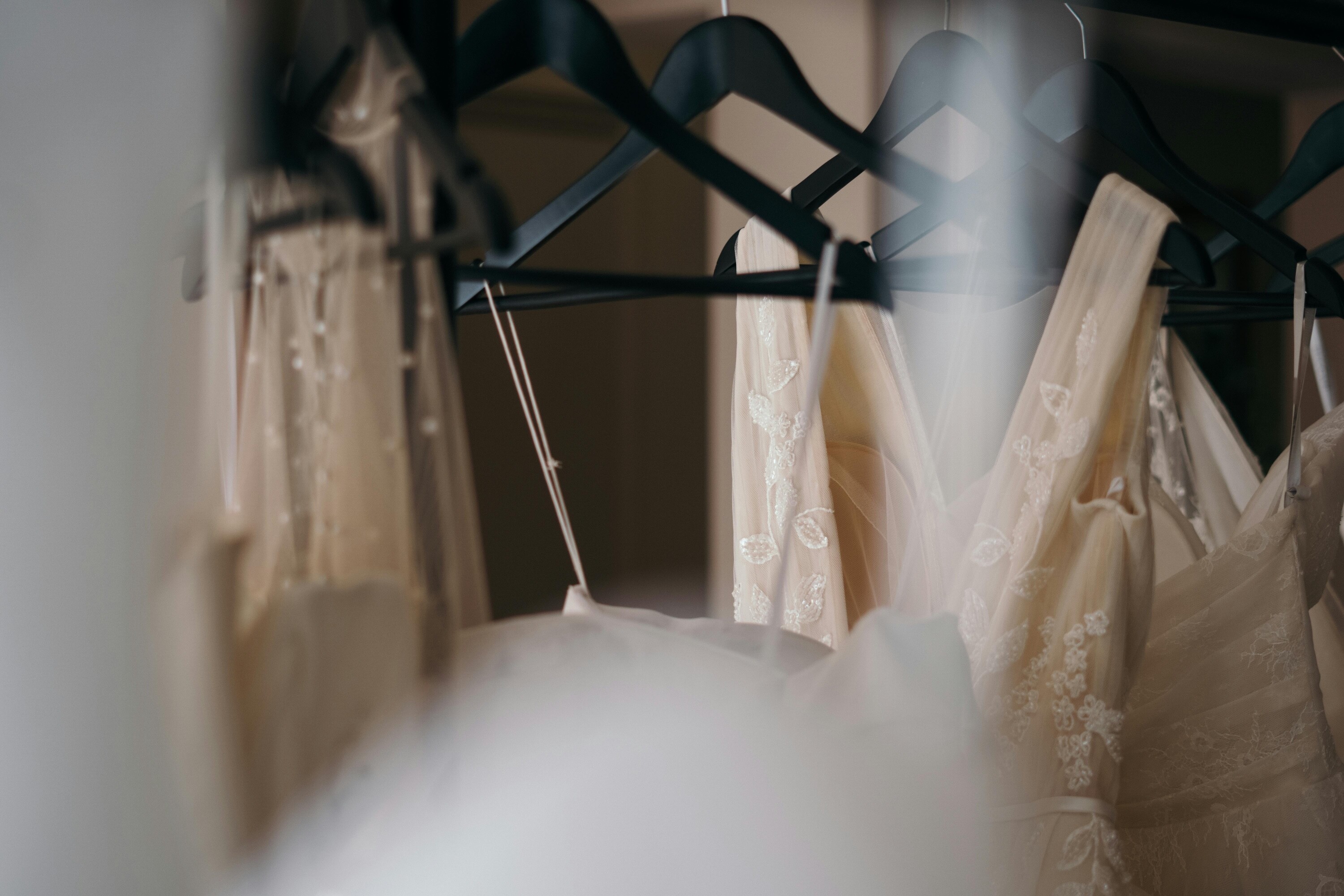 Wedding dresses hanging on rails in a bridal boutique, representing sustainable wedding fashion choices such as made-to-order gowns.
