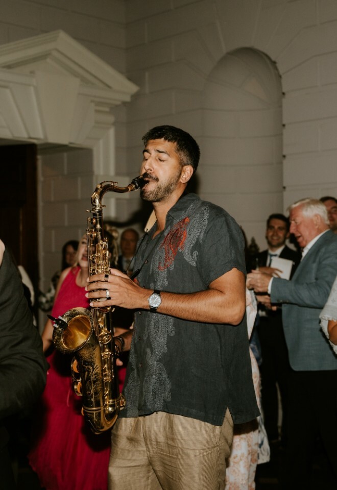 Saxophonist playing the saxophone on the dance floor during the wedding reception