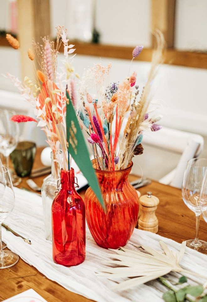 Red vases with dried flowers in for wedding table decor