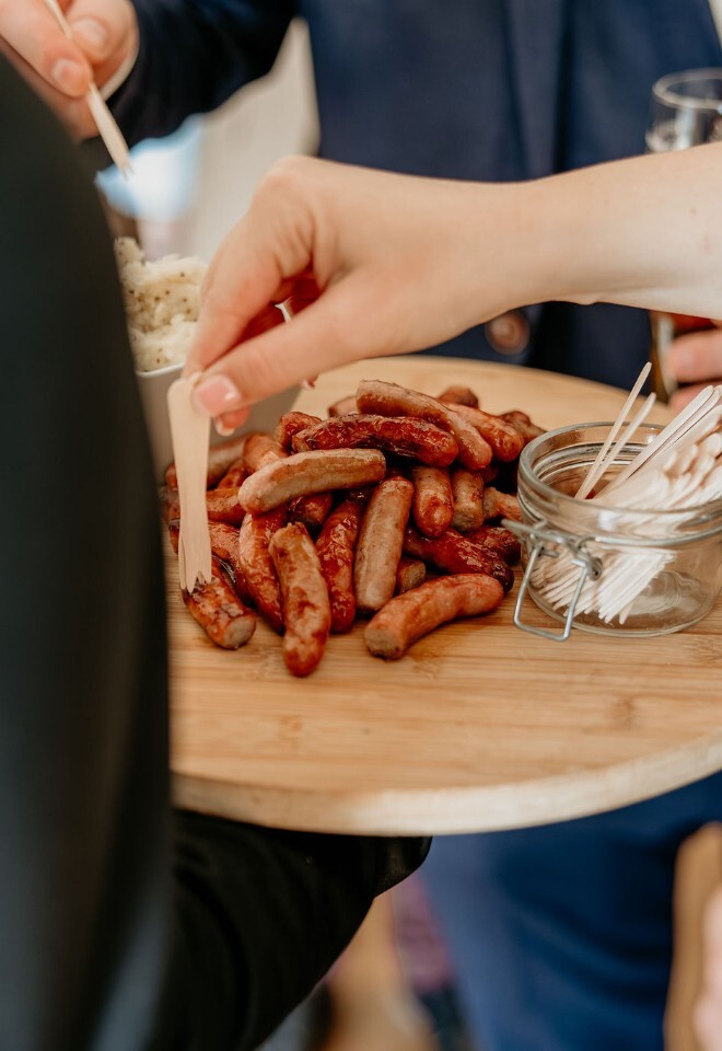 Guests serving sausages from a sharing platter during the reception.
