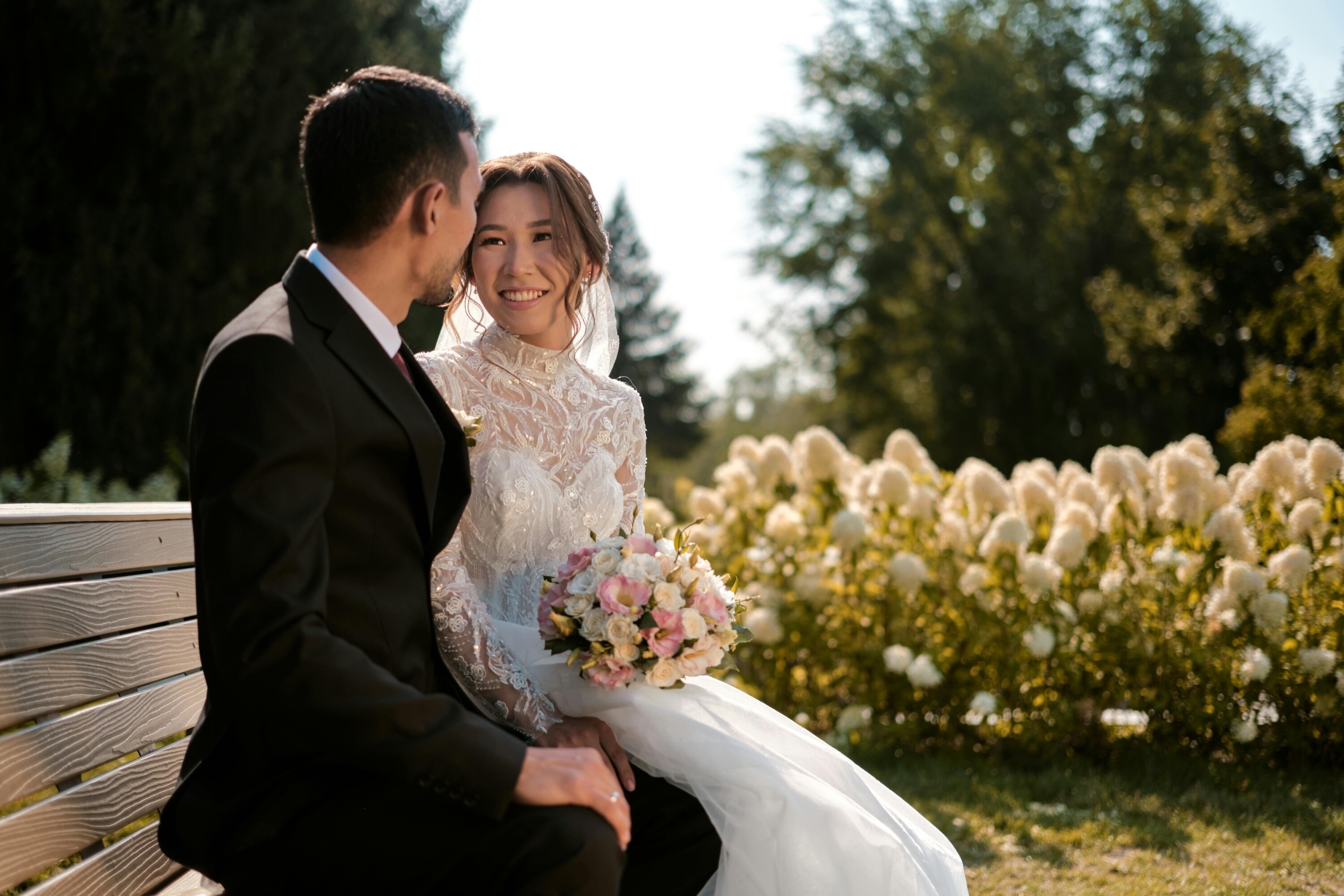 Bride holding round bouquet as she sits next to her groom