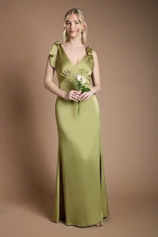 Teen bridesmaid wearing an olive green satin maxi bridesmaid dress with tie shoulder straps and a V-neckline.