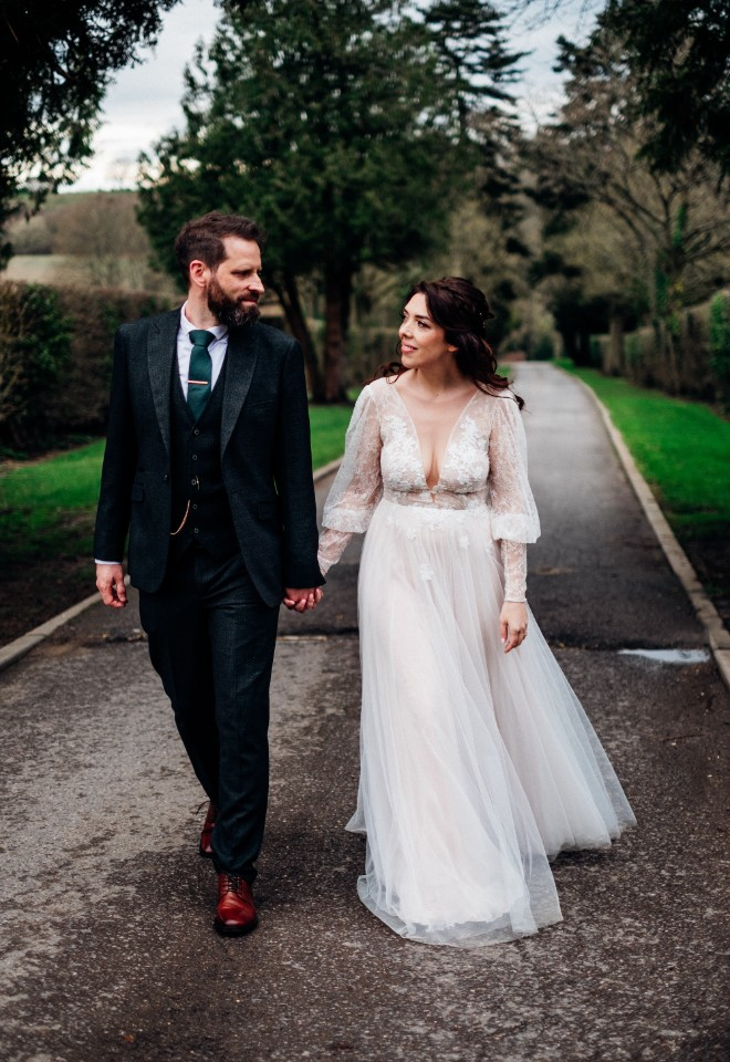 Bride and groom walk hand in hand on the grounds of the venue