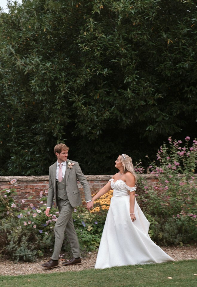 Bride and groom walk through walled garden