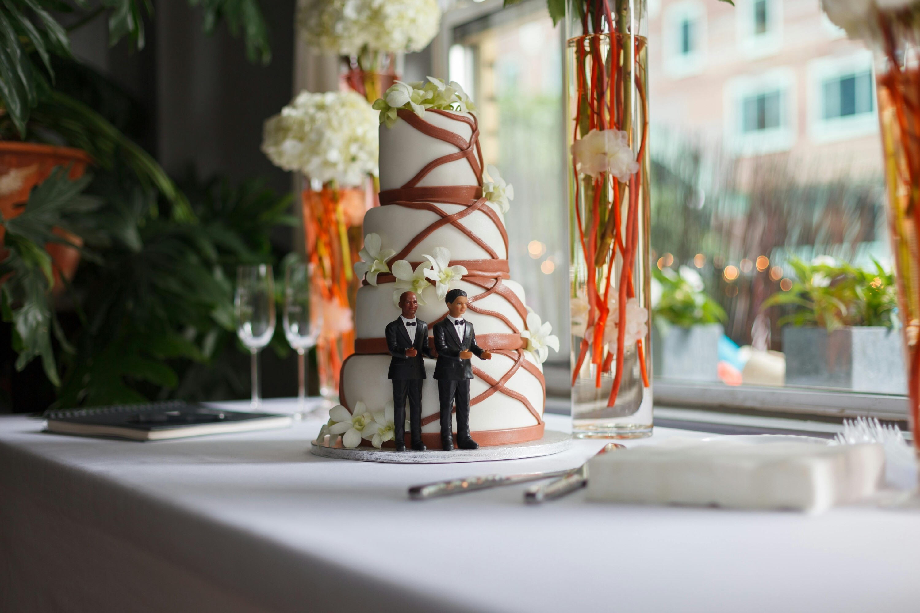 Four tier wedding cake with Groom and Groom figurines next to it.