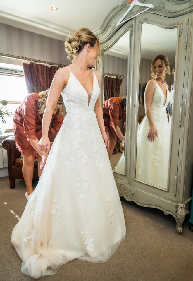 bride trying on wedding dress on wedding morning