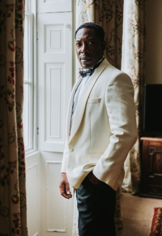 Groom wearing an ivory suit jacket with his hand in his pocket