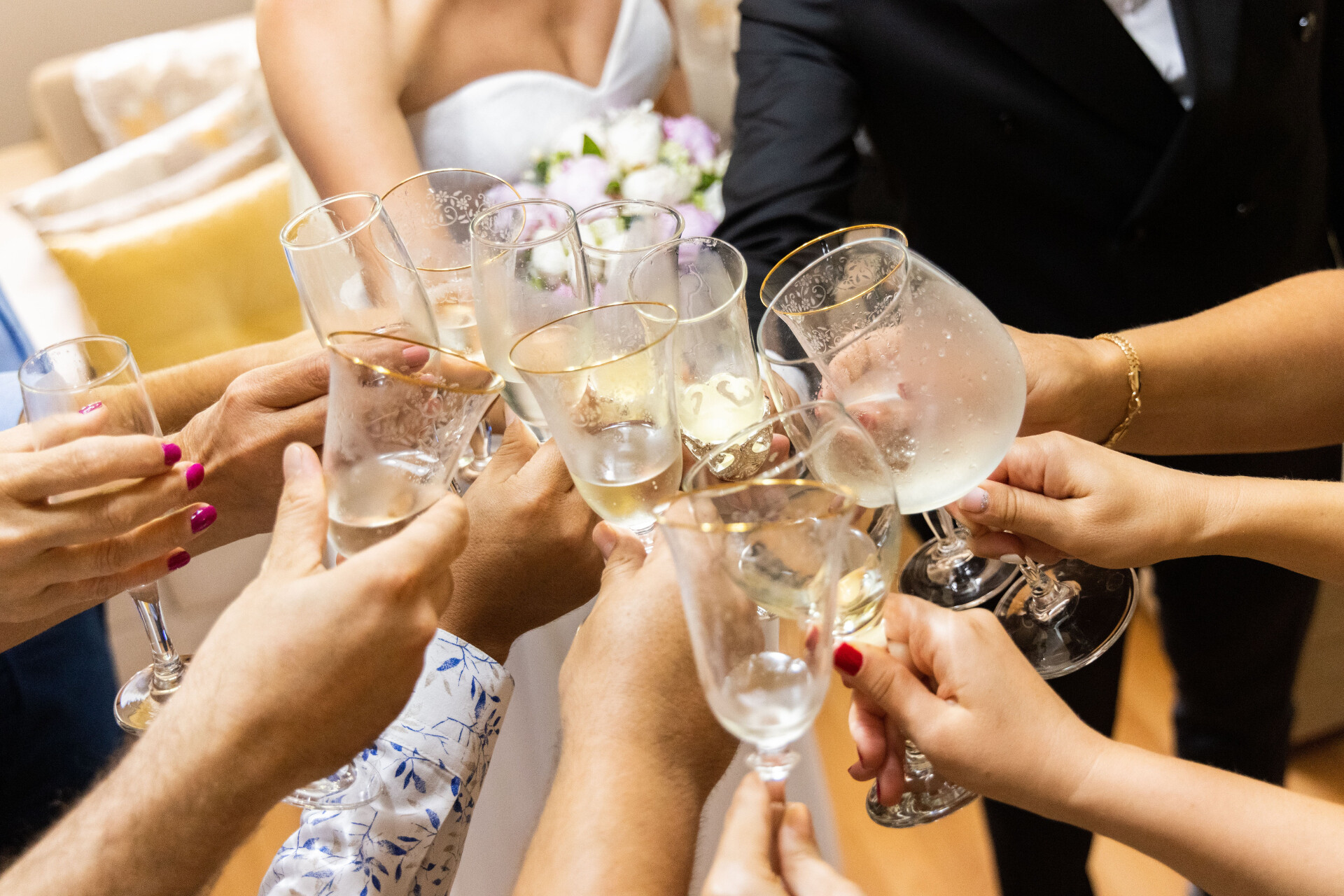 Wedding guests raising champagne glasses during a wedding reception toast.