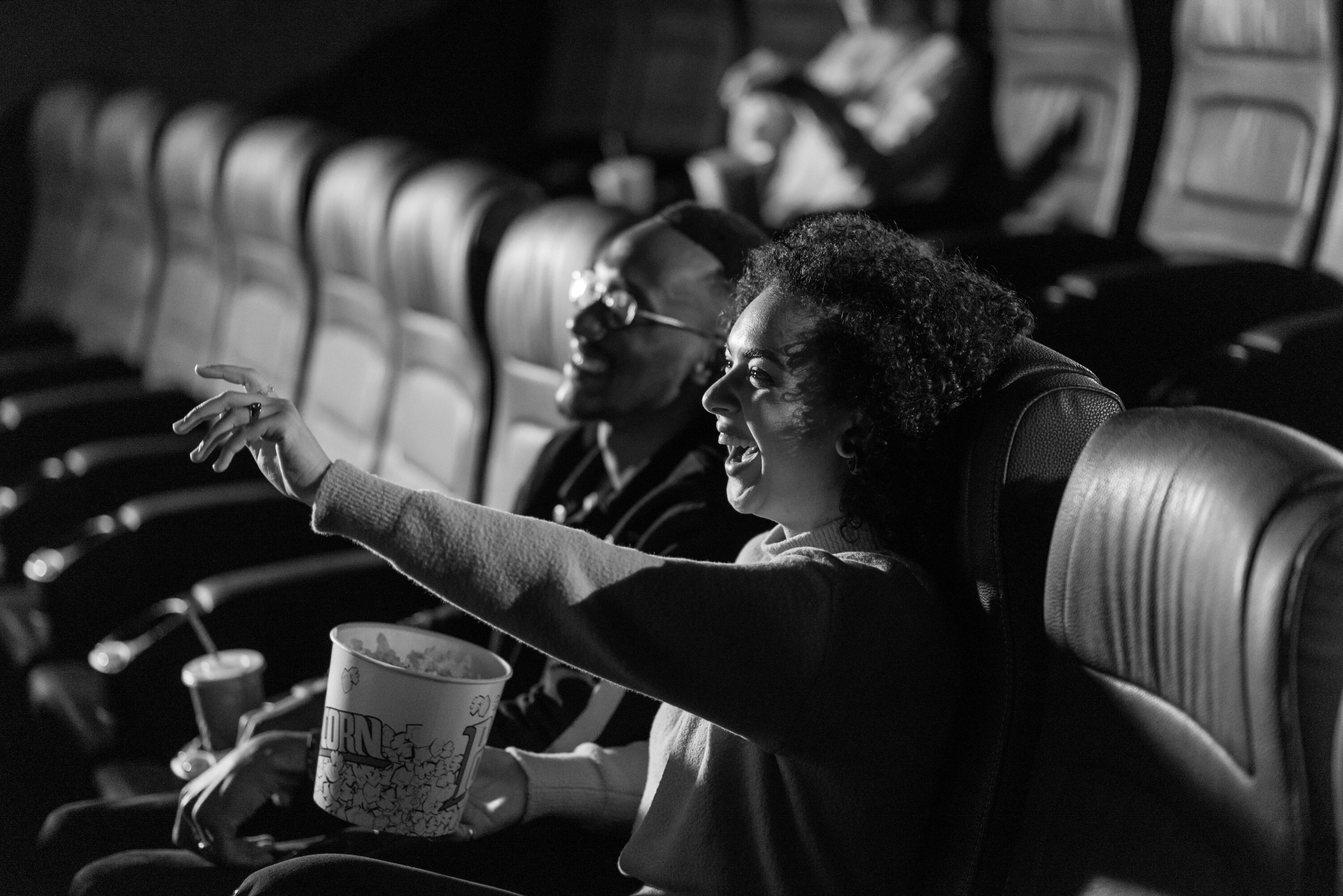 Couple enjoying a cinema date night together while watching a film and sharing popcorn