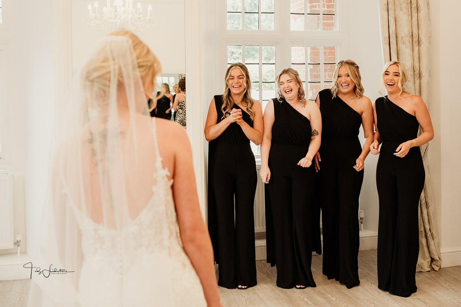 bride reveal with her bridesmaids in black dresses